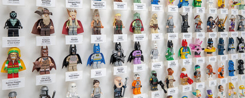 Collection of LEGO minifigures displayed on a wall with name tags underneath.